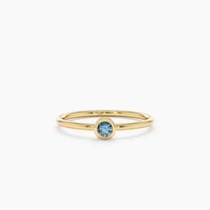 Our Natural Blue Diamond Bezel Ring features a rare and stunning enhanced blue diamond in a modern bezel setting. Handcrafted with solid gold, this dainty ring is perfect for stacking or as an elegant engagement ring.