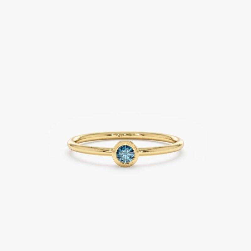 Our Natural Blue Diamond Bezel Ring features a rare and stunning enhanced blue diamond in a modern bezel setting. Handcrafted with solid gold, this dainty ring is perfect for stacking or as an elegant engagement ring.